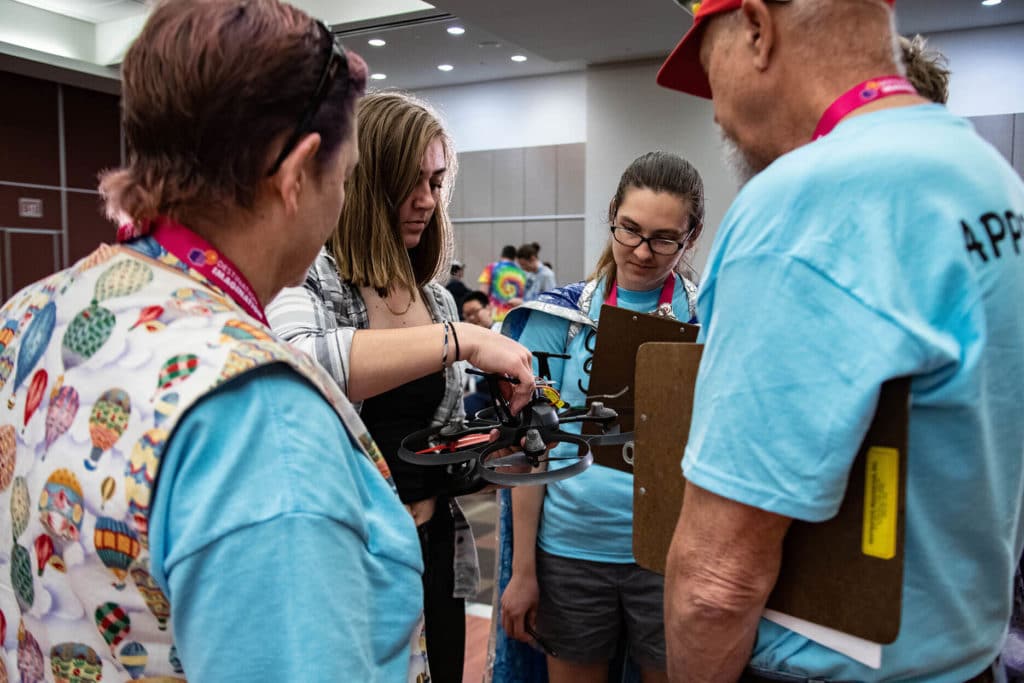 Students and DI Appraisers examine the team's drone in a Technical challenge